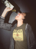 Person wearing a 'Jersey' t-shirt drinking from a bottle against a dark background